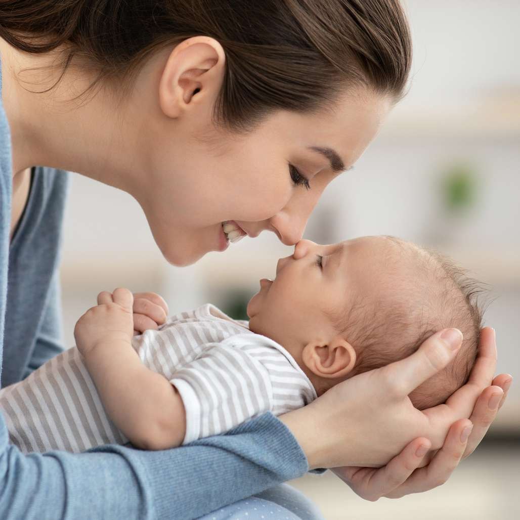 Parent feeding a baby a bottle on a soft blanket